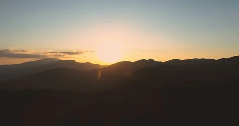 Panoramic view of golden sunset over dark mountain peaks with clear sky Stock Footage 129493745
