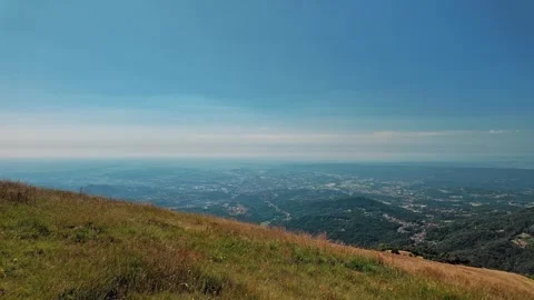 Panoramic view of green mountain valley and distant city under blue sky Video stock 343794722
