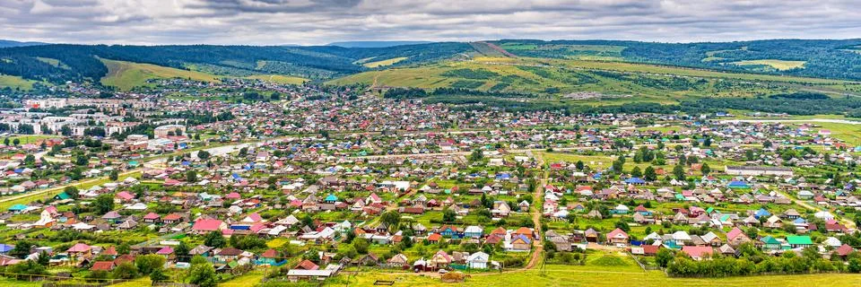 Panoramic view from hill to plain with small town in summer cloudy day. Pictu Stock Photos