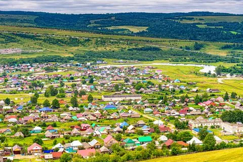Panoramic view from hill to plain with small town in summer cloudy day. Pictu Stock Photos