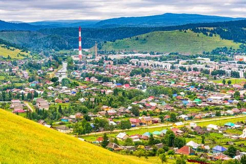 Panoramic view from hill to plain with small town in summer cloudy day. Pictu Stock Photos