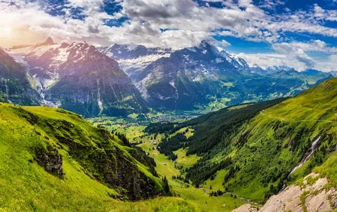 Panoramic view of idyllic mountain scenery in the Alps with fresh green mea.. Stock Photos