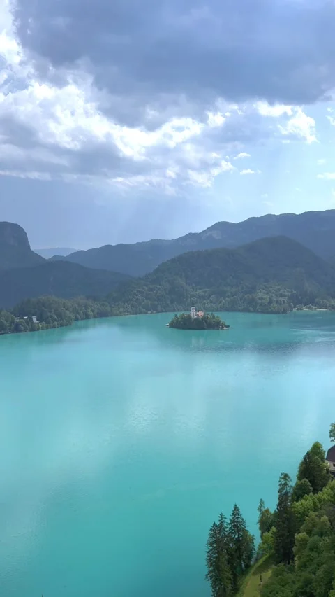 Panoramic view of Lake Bled with island church and mountains under sun rays. The Stock Footage 337356251