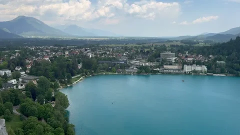 Panoramic view of Lake Bled town with shoreline and mountains under sky. The vid Stock Footage 337534442