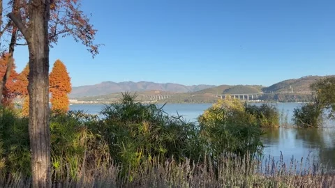 Panoramic view of lake, mountains, wind turbines in golden hour light Stock Footage 323525825
