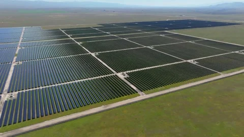 Panoramic view of large solar array farm in lush green valley Stock Footage 303044617
