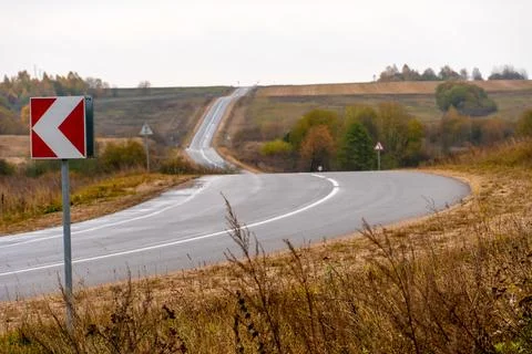 Panoramic view of a long empty asphalt road in a hilly area. The empty windin Stock Photos