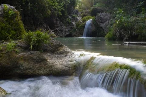 Panoramic view of low waterfall in the forest with long exposure. Stock Photos