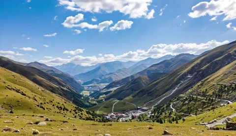 Panoramic view of a lush, green mountain valley under a bright blue sky Stock Footage 321676457