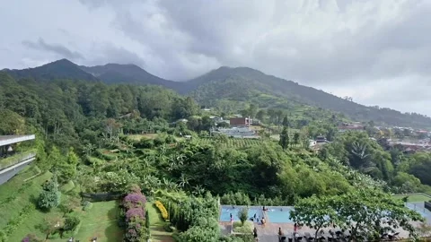 Panoramic view of lush green mountains surrounding vibrant garden with swim.. Видео 331728196