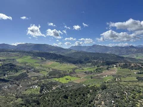 Panoramic view of lush green valleys and distant mountains under a blue sky Stock Photos