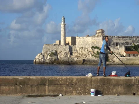 Panoramic view of a man fishing on the seafront at evening Stock Footage 70990474