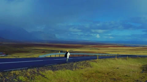 Panoramic view of man in white jacket walking on the road in steppe, Iceland Stockbeeldmateriaal 168078825