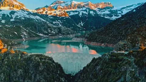 Panoramic view of massive concrete dam holding alpine lake water nestled Stock Footage 343696354