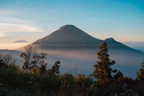 A panoramic view of Mount Sindoro set against a golden-blue sky at sunrise 库存照片