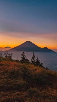 A panoramic view of Mount Sindoro set against a golden-blue sky at sunrise 库存照片
