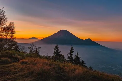 A panoramic view of Mount Sindoro set against a golden-blue sky at sunrise 库存照片