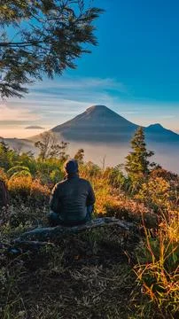 A panoramic view of Mount Sindoro set against a golden-blue sky at sunrise Photos