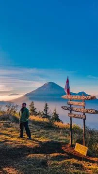 A panoramic view of Mount Sindoro set against a golden-blue sky at sunrise Photos