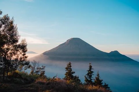 A panoramic view of Mount Sindoro set against a golden-blue sky at sunrise 库存照片