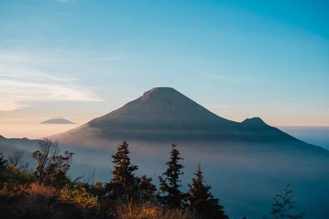 A panoramic view of Mount Sindoro set against a golden-blue sky at sunrise 库存照片