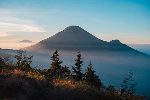 A panoramic view of Mount Sindoro set against a golden-blue sky at sunrise 库存照片