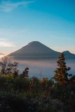 A panoramic view of Mount Sindoro set against a golden-blue sky at sunrise 库存照片