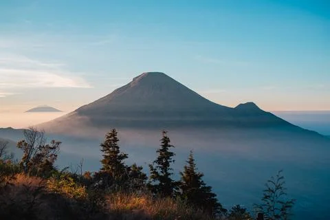 A panoramic view of Mount Sindoro set against a golden-blue sky at sunrise 库存照片