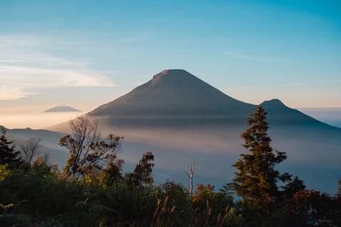A panoramic view of Mount Sindoro set against a golden-blue sky at sunrise 库存照片