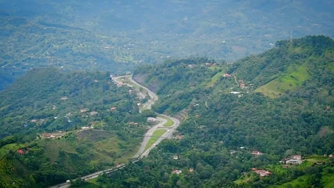 Panoramic view of mountain highway weaving through lush green valley hills Video stock 316792425
