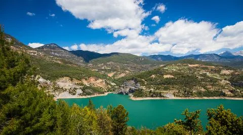 Panoramic view of a mountain lake with clear turquoise-green water against th Stock Photos