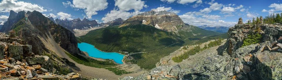 A panoramic view of a mountain range with a blue lake in the foreground Stock Photos