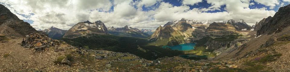 A panoramic view of a mountain range with a blue lake in the foreground Stock Photos