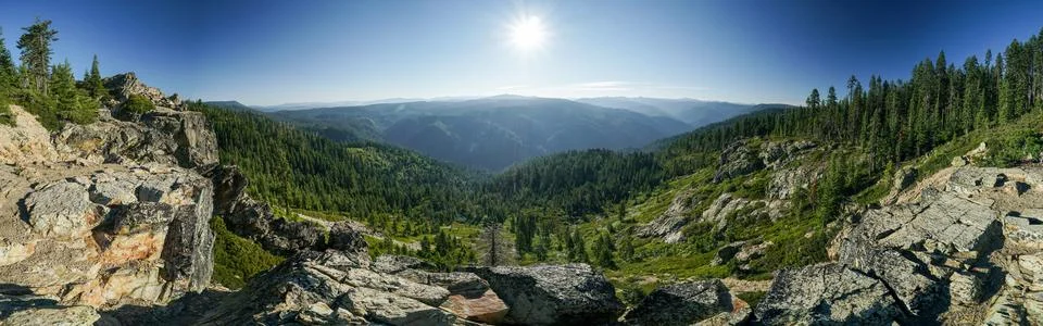 A panoramic view of a mountain range with a bright sun shining down on the .. Stock Photos