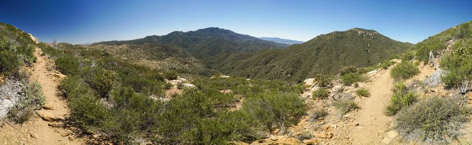 A panoramic view of a mountain range with a dirt path leading to the top Stock Photos
