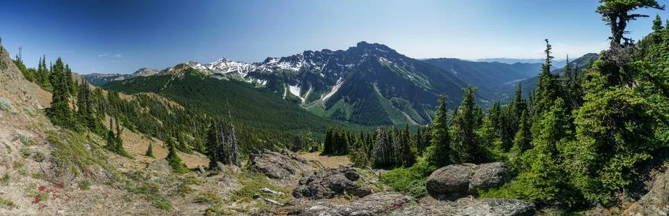 A panoramic view of a mountain range with snow-capped peaks and lush green .. Stock Photos