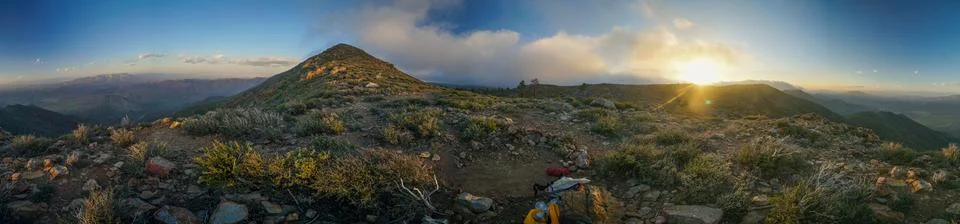 A panoramic view of a mountain range with a sun setting in the background Stock Photos