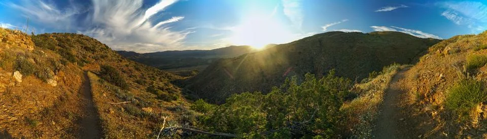 A panoramic view of a mountain range with a sun shining on the trees Stock Photos