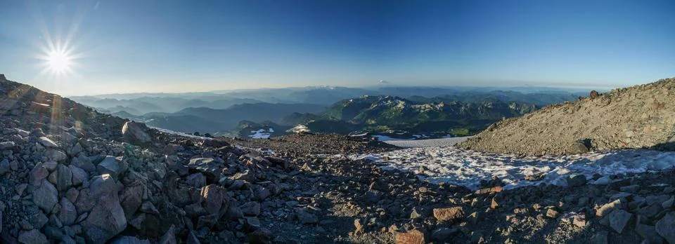A panoramic view of a mountain range with a sun shining on the rocks Foto stock