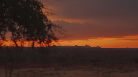 Panoramic view of mountain ranges at sunset with lone tree in foreground. Sun Video stock 312725155
