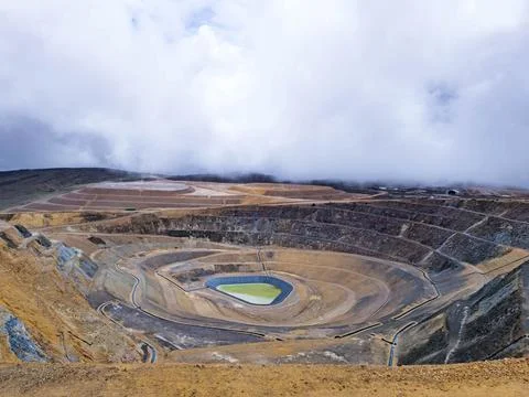Panoramic view of an open pit mine with a lagoon in the background and rain.. Stock Photos