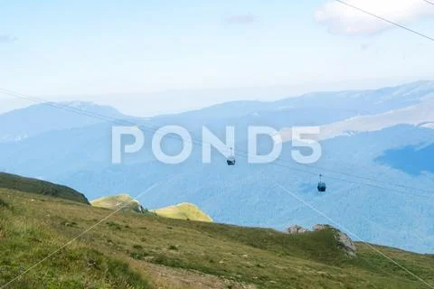 Panoramic view over the Carpatian mountains and two cableway cabins moving to Stock Photos