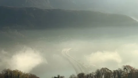Panoramic View over Sea of Clouds over a Highway on Lake with Mountain Stock Footage 165596865