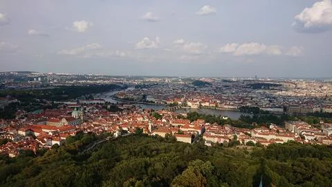Panoramic view of Prague with red rooftops, the Vltava river, and green hills Foto stock