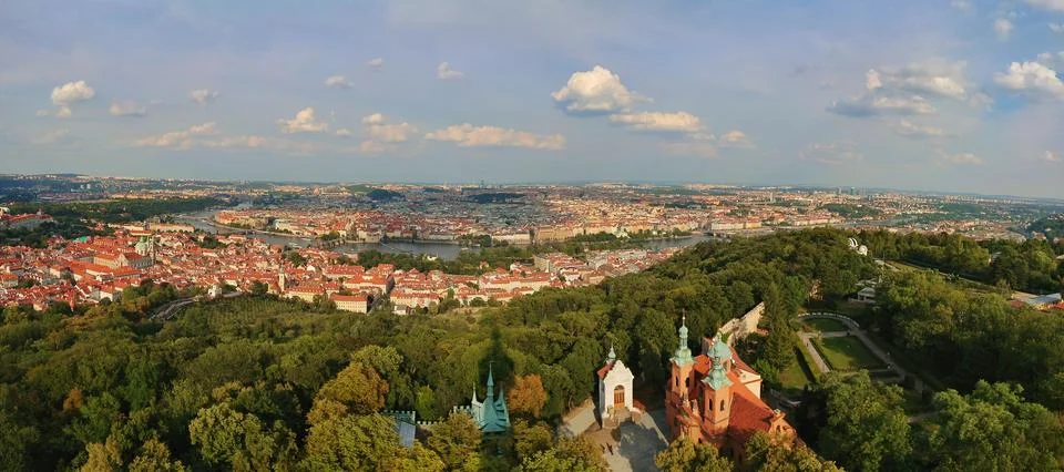 Panoramic view of Prague with red rooftops, the Vltava river, and green hills Stock Photos