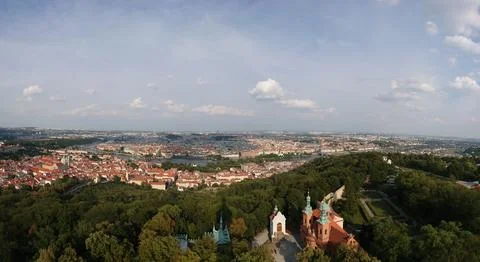 Panoramic view of Prague with red rooftops, the Vltava river, and green hills Foto stock