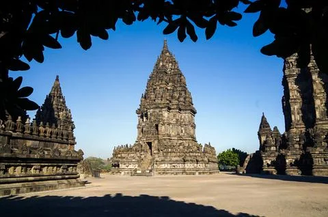 Panoramic view of Prambanan Temple complex framed by shaded tropical tree b.. Stock-Fotos