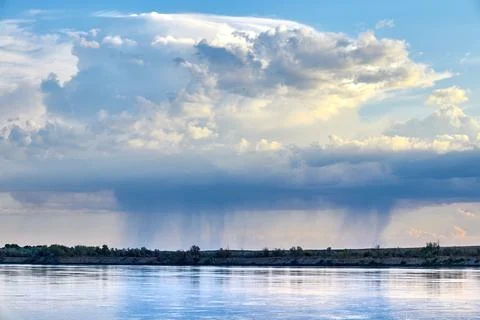 Panoramic view of raining clouds over wide steppe river with a calm current Stock Photos