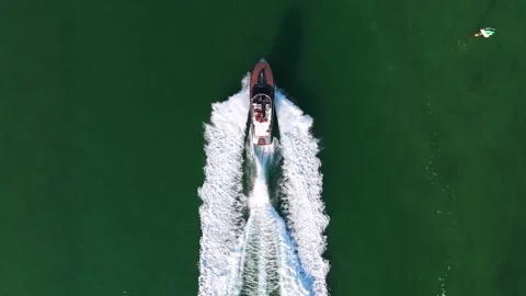 Panoramic view of red and white speedboat moving through green water of large Stock Footage 266944767