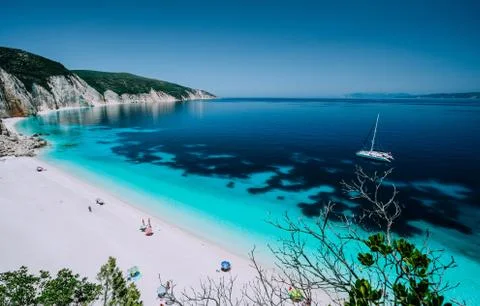 Panoramic view to remote beach wiht lonely white catamaran yacht drift in clear Stock Photos